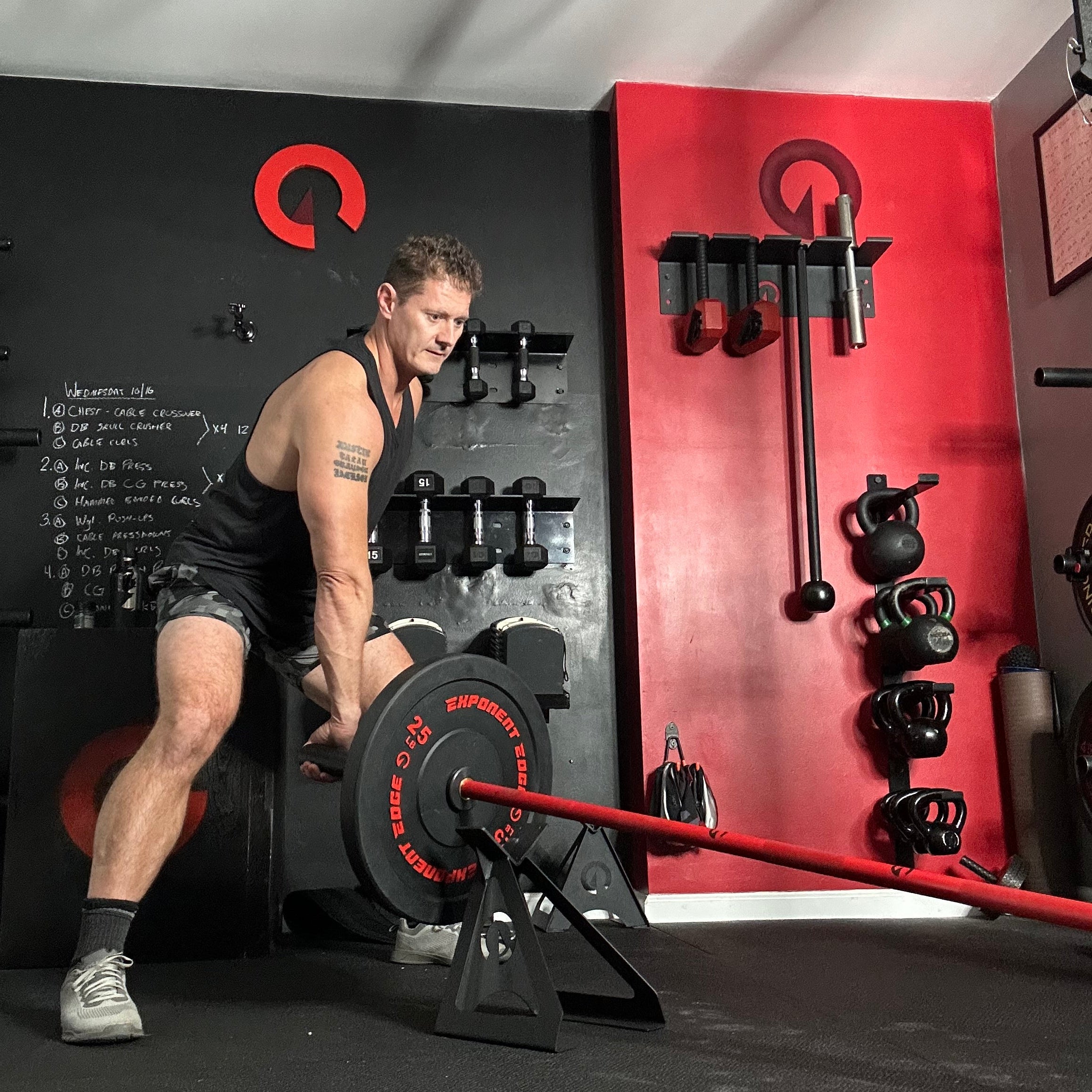 Person lifting weights in a gym setting with red and black equipment.