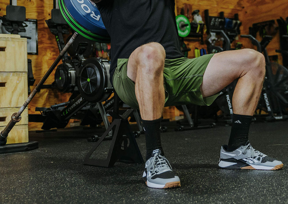 The Edge Landmine Jack is a compact landmine stand that takes the pain out of loading, reloading, and unloading heavy plates onto a barbell while using a landmine. This image presents a man using the Edge Landmine Jack for workouts in a garage gym.