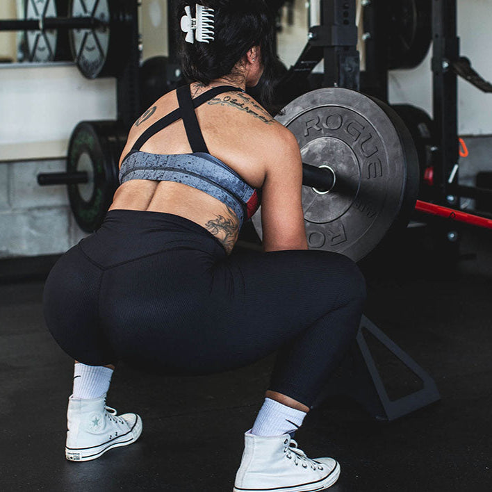 The Edge Landmine Jack is a compact landmine stand that takes the pain out of loading, reloading, and unloading heavy plates onto a barbell while using a landmine. This image presents a women using the Edge Landmine jack for a squat workout.