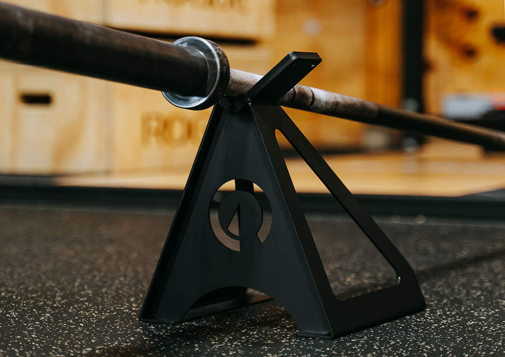 The Edge Landmine Jack is a compact landmine stand that takes the pain out of loading, reloading, and unloading heavy plates onto a barbell while using a landmine. This image presents the Edge Landmine Jack holding an empty barbell.