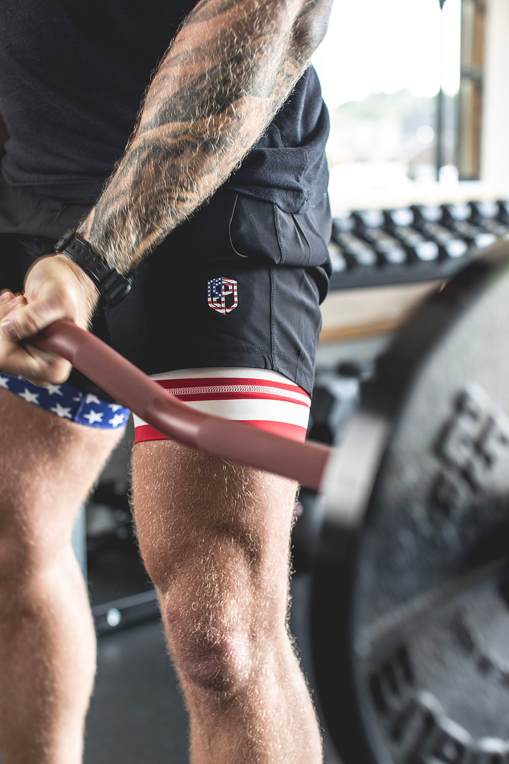 The Edge Bar is a mix between a shortened cambered bar and an EZ Bar. Perfect for enhanced bicep workouts, chest workouts, and more. This image presents the Edge Rackable Cambered Bar being used for a bicep workout.
