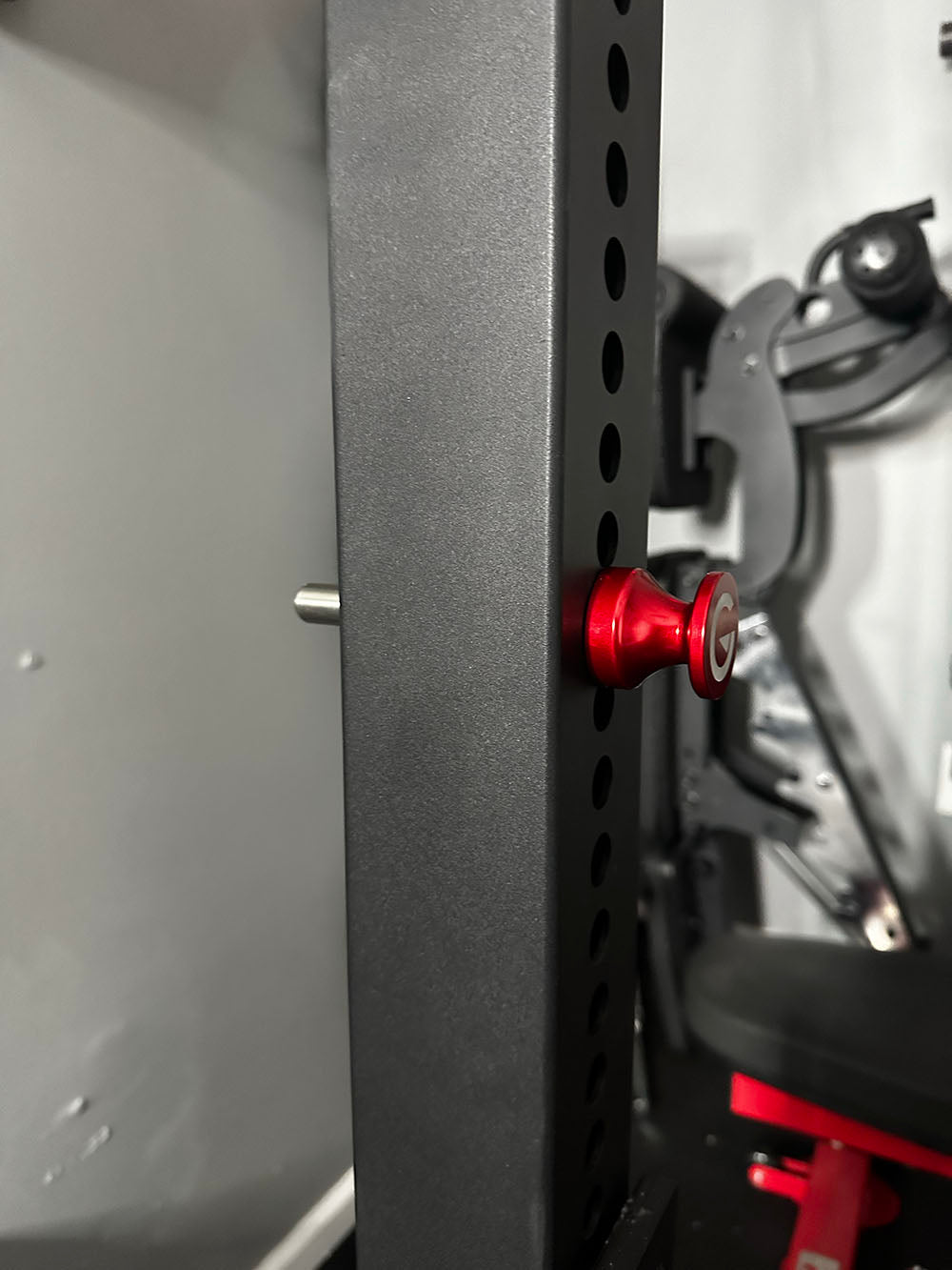Custom Exponent Edge Magnetic pins fit all major brands of squat racks, power racks, and accessories, including Exponent Edge workout equipment. This image presents the Magnetic Edge Pin in red attached to a workout rack from a side view.