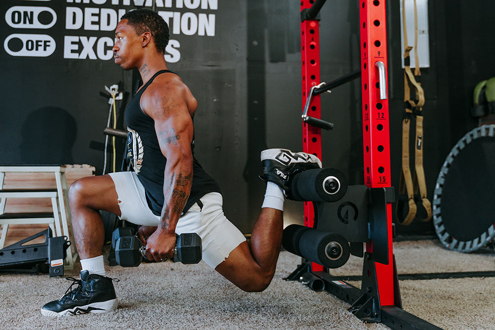 This Rack Mounted Glute Ham Developer is less bulky and lower priced than conventional GHDs. Perfect for glute workouts, ab workouts, and hamstring workouts. This image presents the Rack Mounted Glute Ham Developer being used by a man doing a lunge workout in a garage gym.