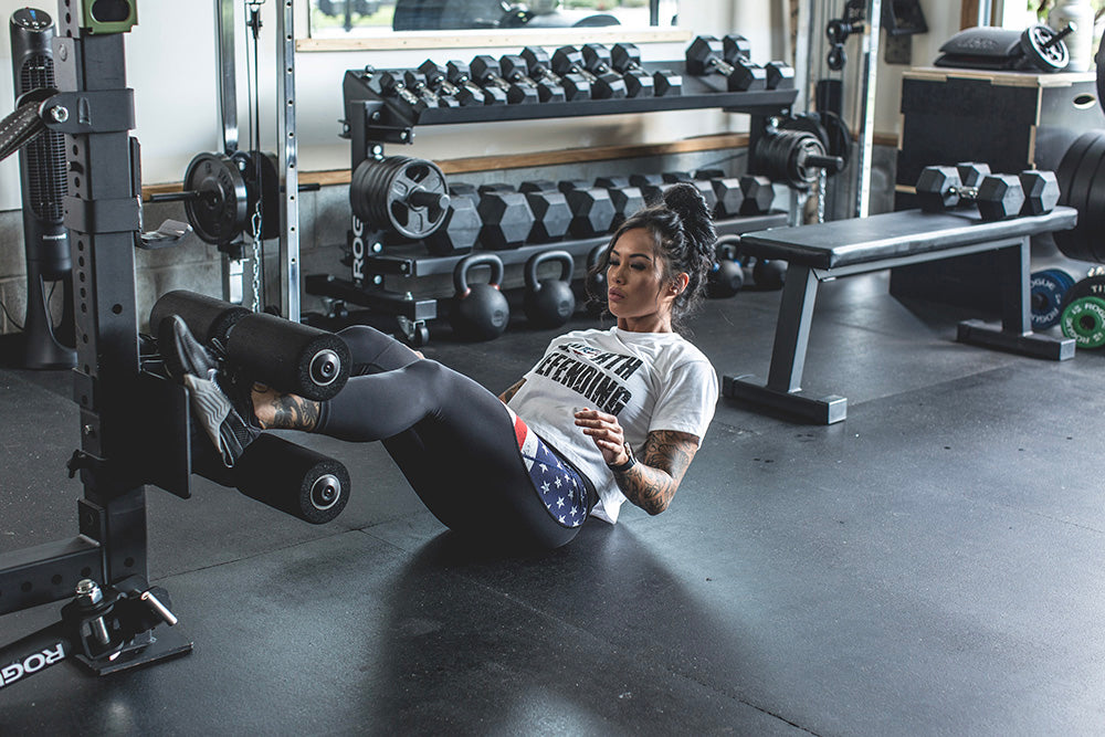 This Rack Mounted Glute Ham Developer is less bulky and lower priced than conventional GHDs. Perfect for glute workouts, ab workouts, and hamstring workouts. This image presents the Rack Mounted Glute Ham Developer being used by a woman for an ab workout in a home gym.
