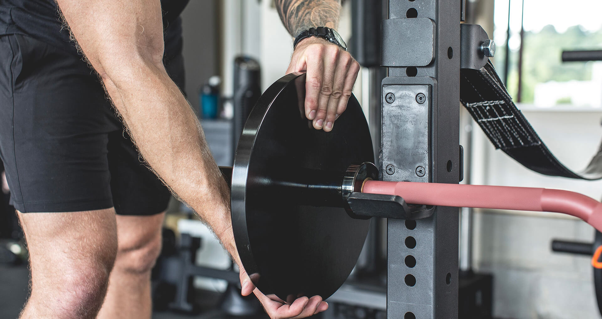 Man putting weights onto the Exponent Edge Rackable Cambered Bar 