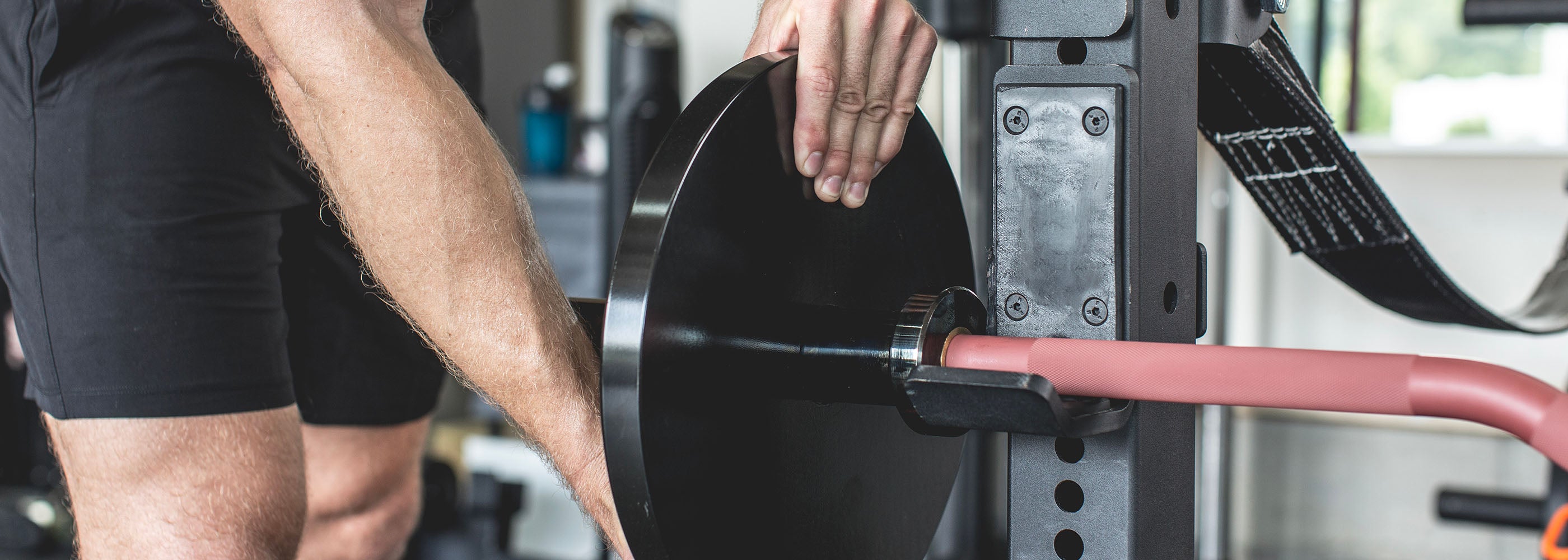 Man putting weights onto the Exponent Edge Rackable Cambered Bar 